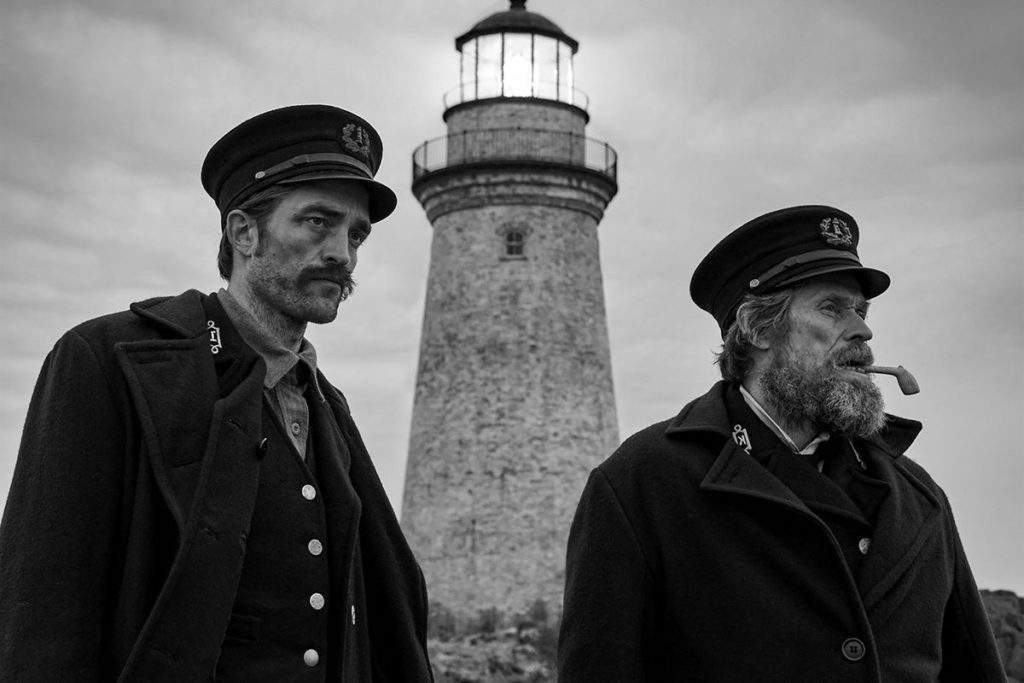 Willem Dafoe and Robert Pattinson in Robert Eggers' The Lighthouse, reviewed at Riot Material magazine.